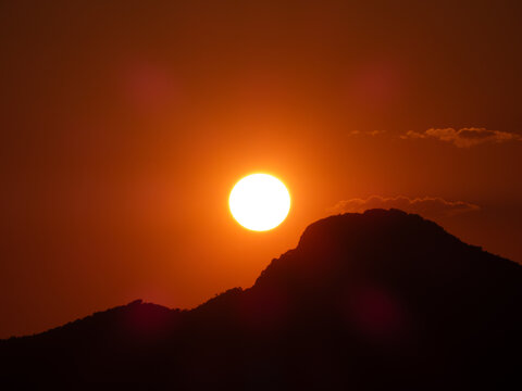 Scenic landscape view of a vibrant red sunset behind the hills, casting a deep red glow across the entire sky and environment.
