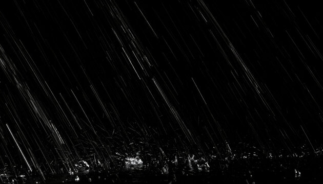 Heavy rain falling diagonally against a completely black background creating a dramatic and intense atmospheric effect with splashes on the ground