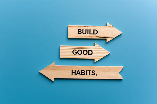 Wooden arrows pointing forward with "BUILD GOOD HABITS," text for progress and motivation. Success concept.