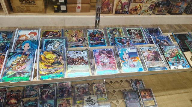 Chantilly, Virginia, USA &ndash; September 20, 2026: One Piece Card Game collectible cards are laid out in a shop display case. Rare and shiny cards featuring anime characters, encased in protective sleeves