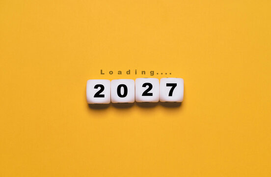 2027 New Year loading concept with white number blocks and Loading text on yellow background symbolizing countdown to fresh beginnings, future business planning and upcoming opportunities.