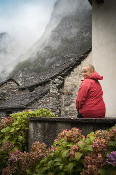 Woman explores traditional stone houses in misty Roseto, Switzerland, ideal for rural travel