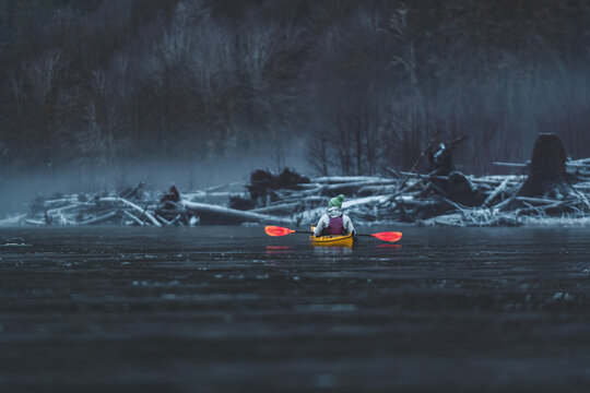 Person in yellow kayak on a cold winter lake