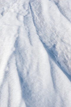 Snow ice. the ice crust. Close-up view of fresh, fluffy snow covering the ground, showcasing a textured surface with varying shades of white and soft contours