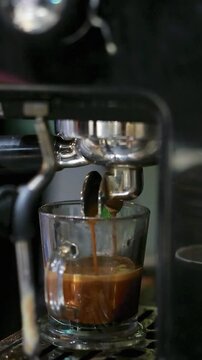 Rich espresso pours into a clear glass cup