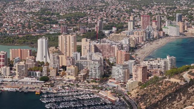Panoramic aerial drone footage of a densely populated coastal city with a marina and beach.