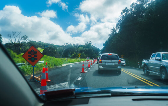 Temporary redlight sign and 30 km/h road sign by the road. Traffic slowing on the road. Roadworks in Auckland.