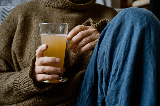 Person in Knit Sweater Holding Glass of Warm Apple Cider
