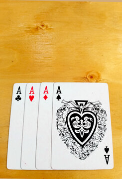 Four Aces Playing Cards Fanned Out on Wooden Table
Four Ace playing cards are neatly fanned out on a light wooden table surface.