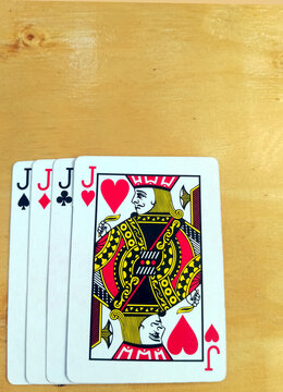 Four Jack Playing Cards Fanned Out on Wooden Table
Four Jack playing cards are neatly fanned out on a light wooden table surface.