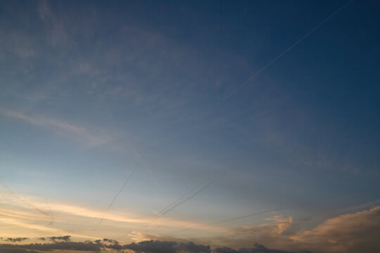 Dramatic Sunset Sky with Clouds and Airplane Contrails