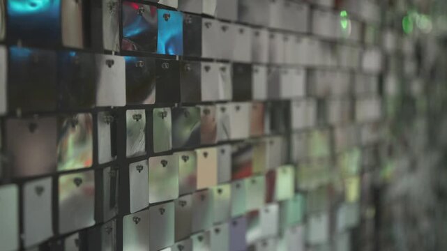 Abstract mirror mosaic wall texture with reflective rectangular glass tiles, colorful blurry light bokeh, modern shiny decorative surface background pattern.