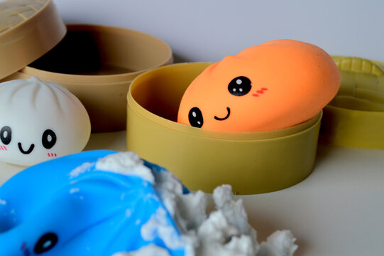 Cute kawaii squishy dumpling and bun toys with smiling faces displayed inside miniature bamboo steamer baskets on a soft background