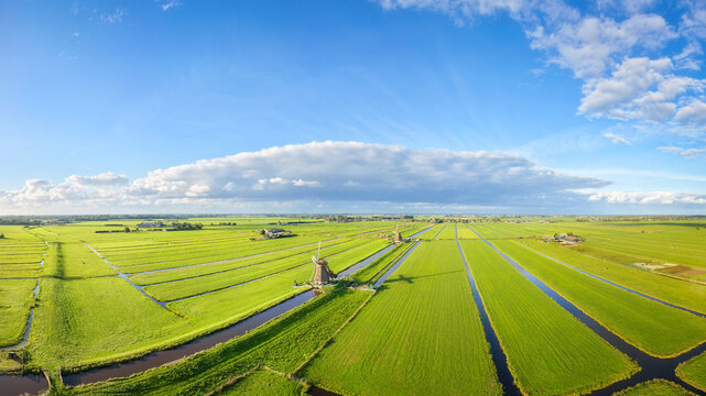 Aerial drone view of traditional windmills in the Netherlands. Panoramic view. Green fields and rural countryside landscape in the Dutch region.