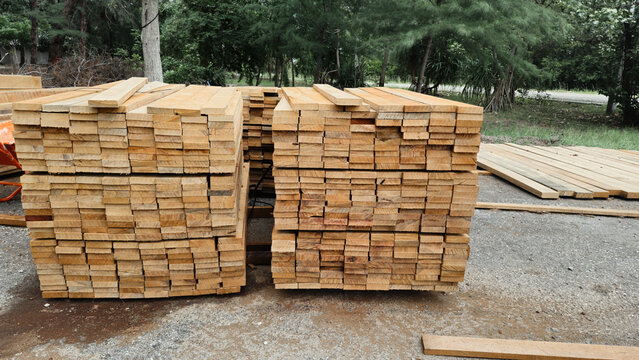 Stacked wooden planks stack of lumber timber boards for construction industry. Raw pine wood material in sawmill factory outdoor yard background.
