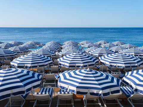 Sun umbrellas and sunbeds on a sandy beach by the sea. Summer vacation and travel resort on a sunny day. A place to rest and relax.
