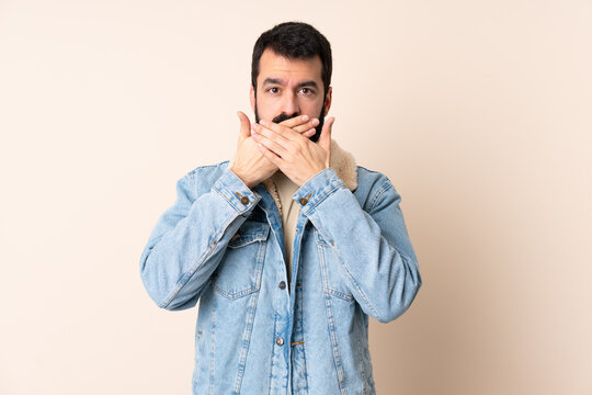 Caucasian man with beard over isolated background covering mouth with hands