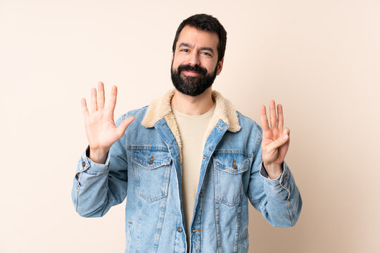 Caucasian man with beard over isolated background counting eight with fingers