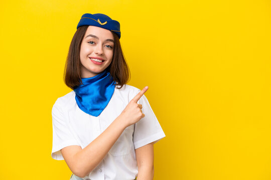 Airplane stewardess Ukrainian woman isolated on yellow background pointing to the side to present a product