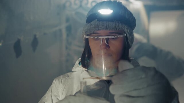 Abandoned house researcher retrieves contaminated vial under headlamp in frostbound corridor wearing protective suit gloves face shield careful evidence handling nuclear fallout atmosphere cinematic