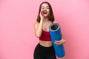 Young sport Ukrainian woman going to yoga classes while holding a mat isolated on pink background with surprise and shocked facial expression © luismolinero