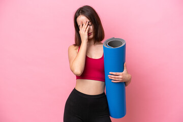 Young sport Ukrainian woman going to yoga classes while holding a mat isolated on pink background with tired and sick expression © luismolinero