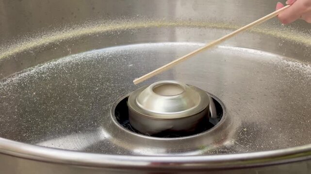  Cotton candy machine close-up: stick starts collecting sugar floss inside stainless bowl