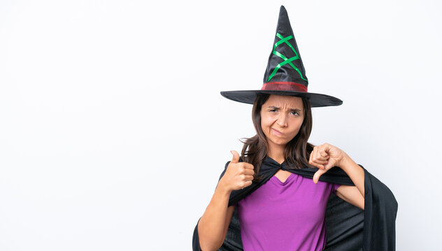 Young hispanic woman dressed as witch over isolated background making good-bad sign. Undecided between yes or not