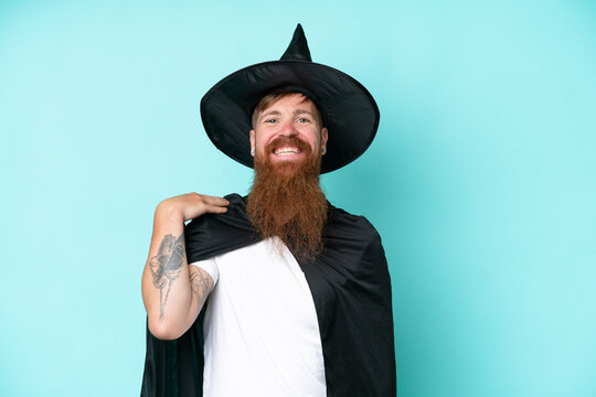 Young wizard in halloween isolated on blue background laughing