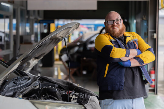 Mechanic poses with a car at a workshop
