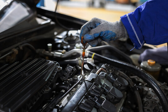 Worker checks oil level in car engine during maintenance session in garage