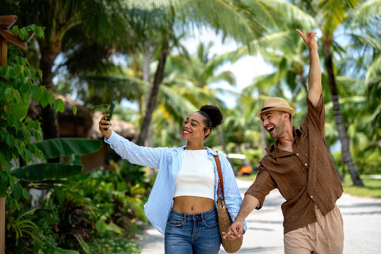 Diverse interracial couple sharing a joyful and intimate moment in a tropical park, beach