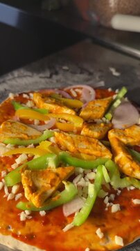 Chef adding paneer tikka toppings on pizza base vertical video close up
