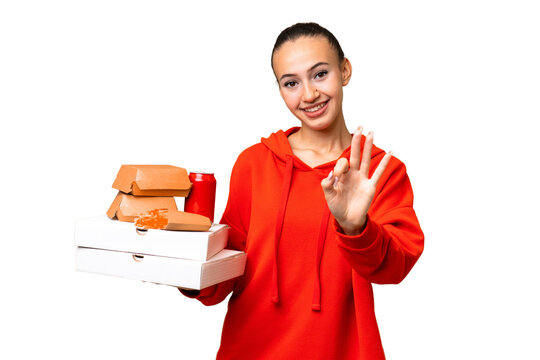 Young Arab woman holding fast food over isolated background happy and counting three with fingers