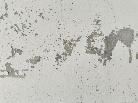 Weathered white wall texture with peeling gray paint  distressed surface  abstract grunge pattern  aged concrete background  rustic backdrop  and vintage architectural detail for design use.