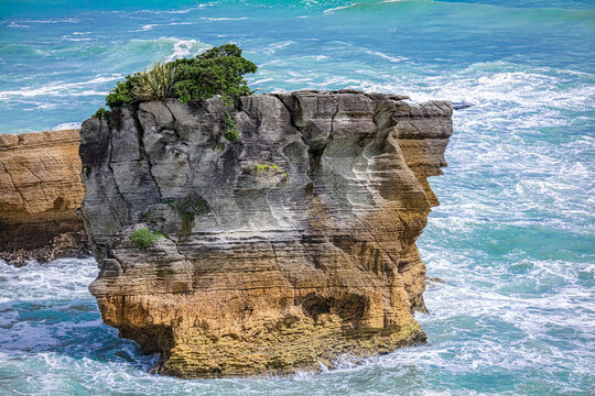 Zerkl&uuml;fteter Felsenstack mit gr&uuml;ner Vegetation im t&uuml;rkisen Meer bei den Pancake Rocks, Punakaiki, Neuseeland