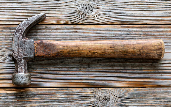 single vintage hammer lying on a rustic wooden floor, worn wooden handle with metal head showing signs of use, soft natural window light casting subtle shadows