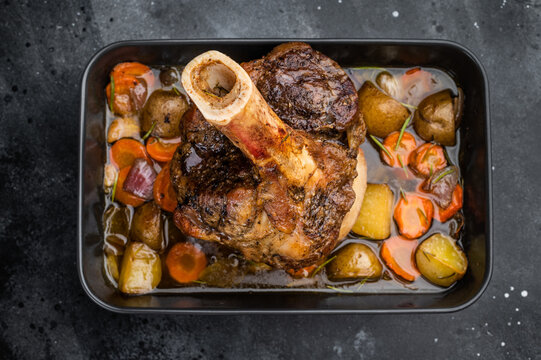 Juicy braised beef shank ossobuco cooked with potatoes carrots herbs and flavorful sauce