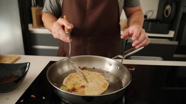 Professional chef preparing a delicious quesadilla with a spatula in a modern kitchen