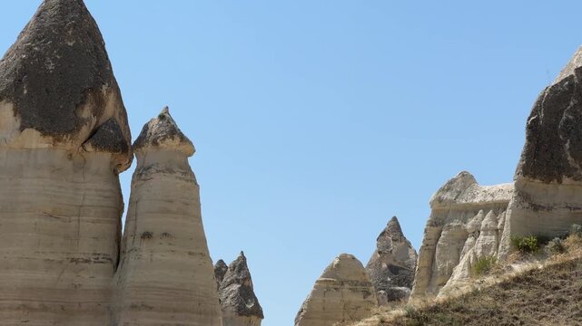 Scenic path through Love Valley in Cappadocia, Turkey, surrounded by cream colored rock formations and dry hillsides. Iconic geological travel landscape.