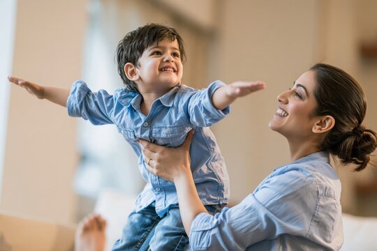 Mother lifting her happy little boy up in the air pretending to fly at home