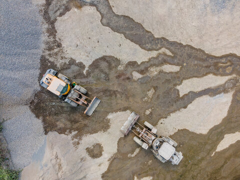 Wheel Loader Working in a Rock and Sand Quarry in Indonesia. Quarry Floor with Distinctive Ground Patterns Surround the Heavy Earthmoving Machine, Industrial Mining Site view from above.