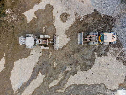 Wheel Loader Working in a Rock and Sand Quarry in Indonesia. Quarry Floor with Distinctive Ground Patterns Surround the Heavy Earthmoving Machine, Industrial Mining Site view from above.