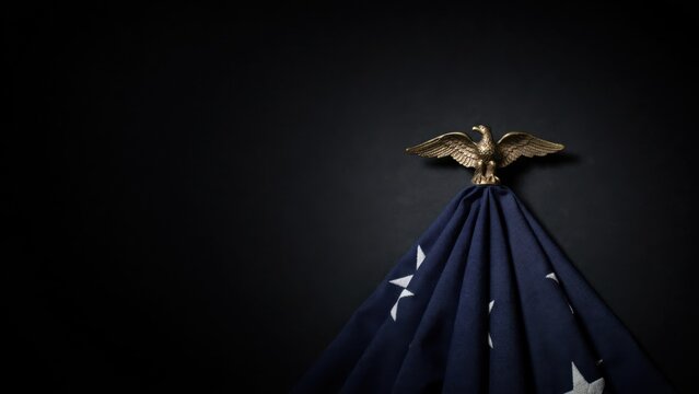 Patriotic American flag with golden eagle finial on black background