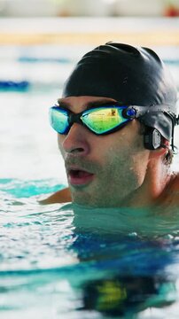 Swimmer adjusts goggles underwater, focused and determined. Water ripples around head, capturing intense training moment. Ideal for fitness, sports, or aquatic event promotions