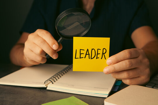 Leadership text on sticky note with businessman working at office desk.