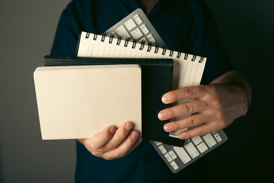 Businessman holding folders and computer keyboard on dark background, closeup