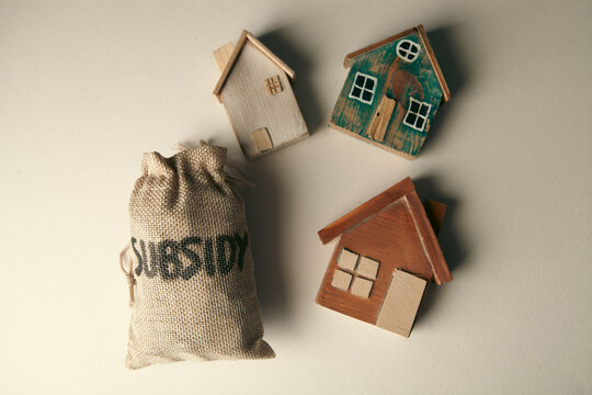 Money bag with house model on dark background. Real estate concept.