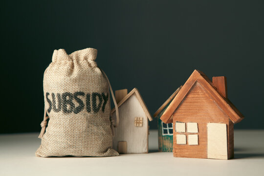 Money bag with house model on dark background. Real estate concept.