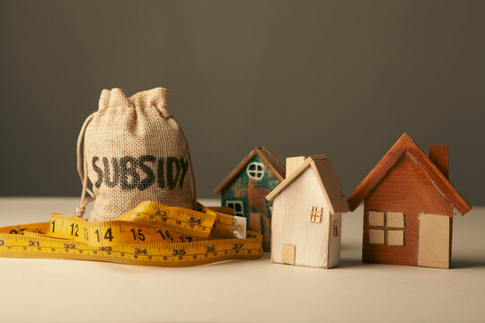 Money bag with house model on dark background. Real estate concept.
